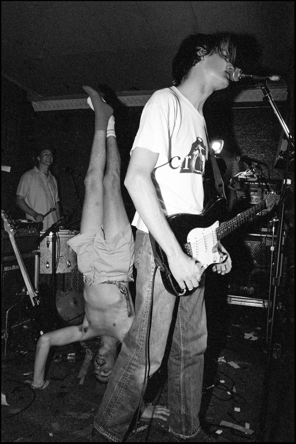 Pavement on stage at Maxwell’s with drummer Gary Young doing a headstand beside Stephen Malkmus singing and Scott Kannberg on guitar, Hoboken, New Jersey, 1992, photographed by David Corio.