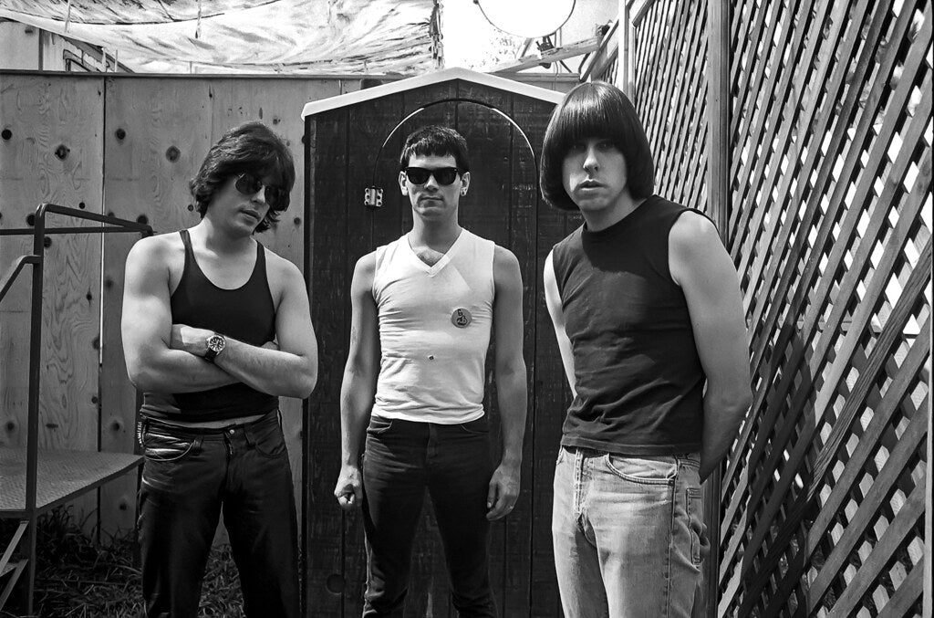 Three Ramones against a lattice fence, in black and white, 1982, photographed by Lynn Goldsmith.