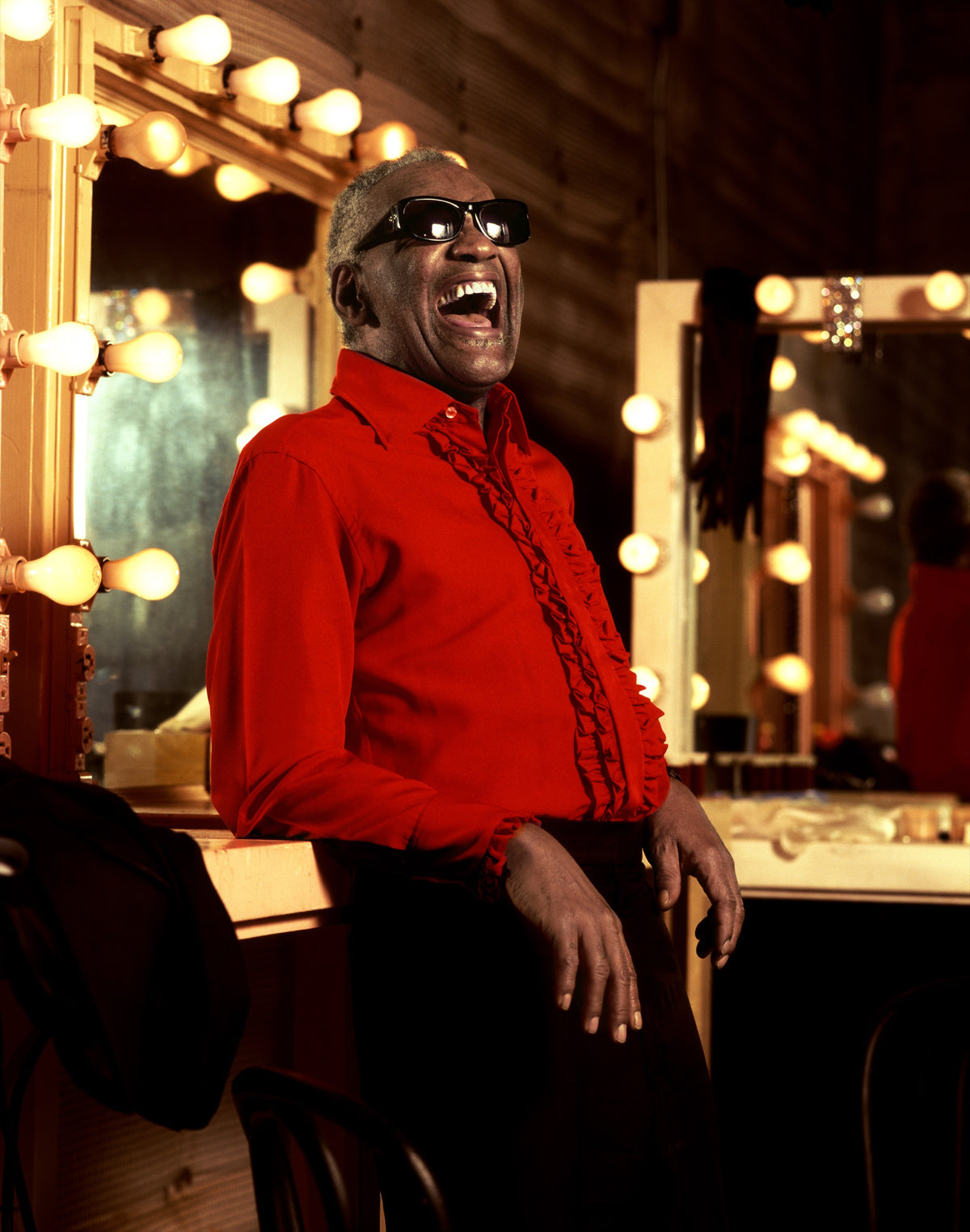 Ray Charles stands in a bright red shirt beside an illuminated dressing-room mirror. Photograph by Timothy White, Culver City, California, 1992.