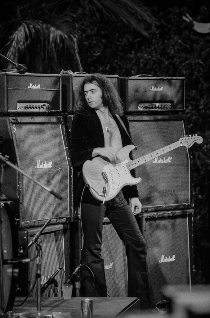 Ritchie Blackmore playing guitar before a wall of amplifiers, in black and white, 1974, photographed by Lynn Goldsmith.