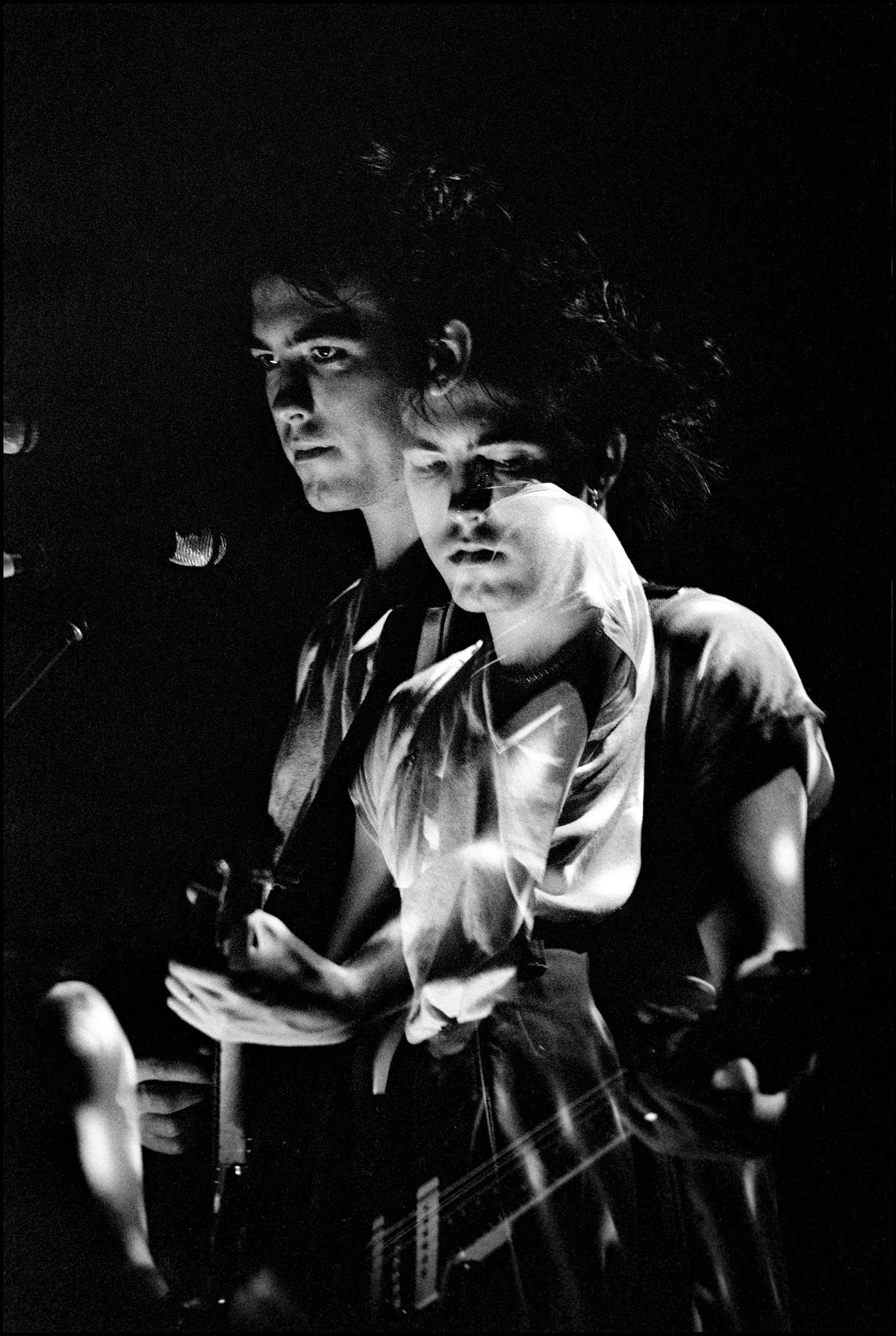 A long-exposure image capturing two overlapping figures of Robert Smith of The Cure playing guitar under strobe light, Brighton, 1982, photographed by David Corio.