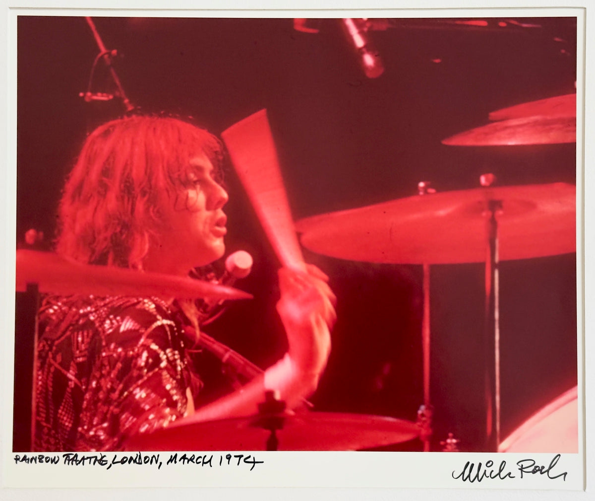 Roger Taylor of Queen drumming at the Rainbow Theatre, London, March 1974, in red stage light — photograph by Mick Rock, a signed, hand-titled late print.