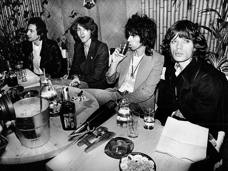 The Rolling Stones gathered around a table with food and drinks in 1972. Photograph by Gijsbert Hanekroot.
