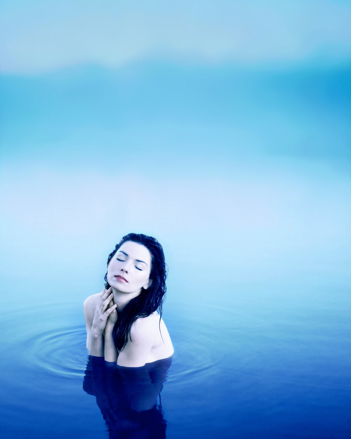 Shania Twain rises from calm blue water in a portrait dominated by cool tones. Photograph by Timothy White, Lake Placid, New York, 1997.