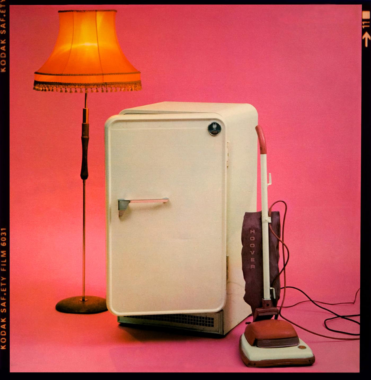 The Cure's Three Imaginary Boys album cover image, a lampshade, a fridge and a Hoover vacuum on a hot-pink background, photographed by Martyn Goddard, 1979.