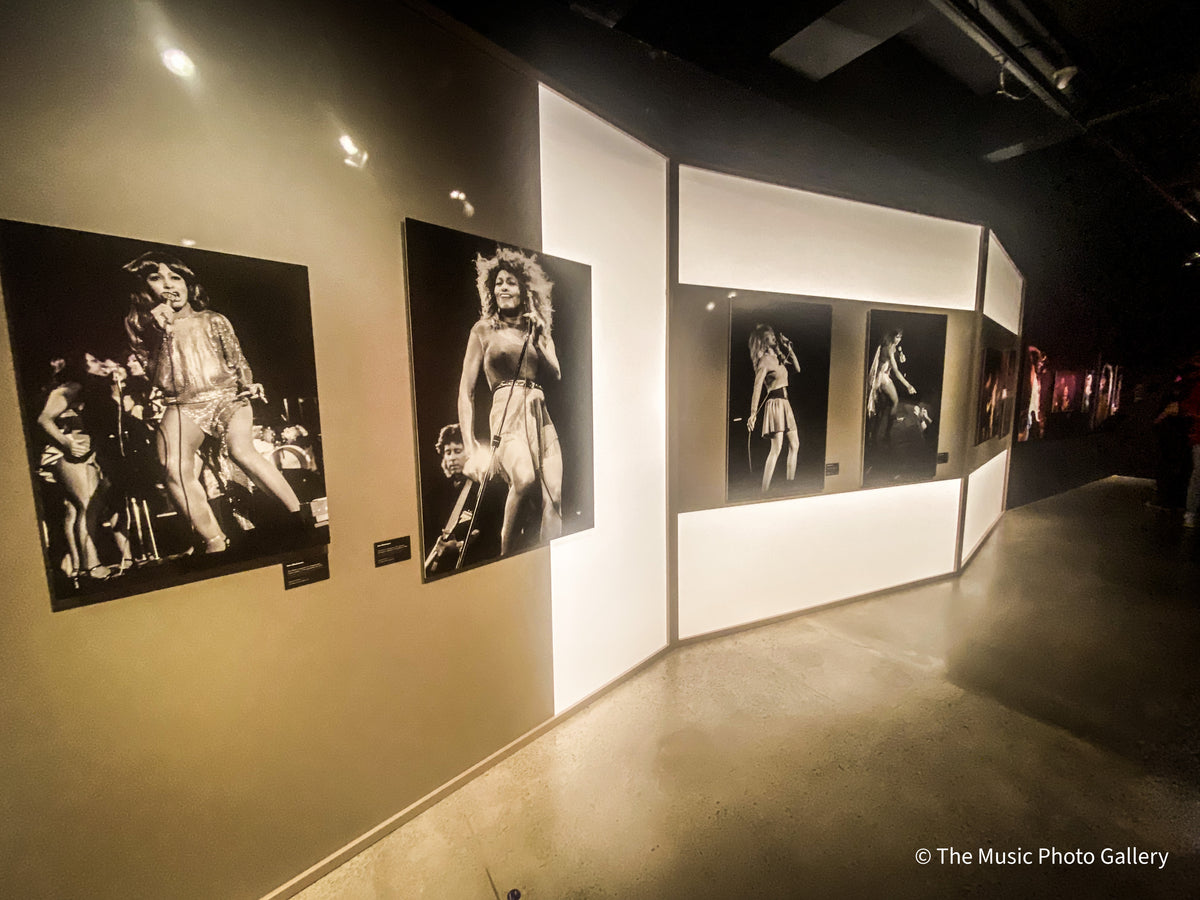 Black-and-white concert photographs of Tina Turner on illuminated display walls in Tina Turner: A Journey to the Future at the Museum of Image and Sound (MIS), São Paulo, Brazil.